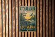 A vintage-style metal sign for the Atchafalaya National Wildlife Refuge in Louisiana, featuring an illustration of wildlife and a serene landscape.