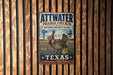 A vintage-style metal sign for the Attwater Prairie Chicken National Wildlife Refuge in Texas, featuring an illustration of a bird in a field with a windmill and water tower in the background.