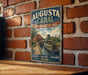 A vintage metal sign for the Augusta Canal in Georgia, featuring an illustration of a canal with a boat and buildings, mounted on a brick wall.