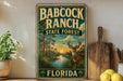 A vintage metal sign for Babcock Ranch, Florida, featuring a scenic landscape with a deer and palm trees.