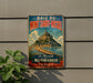 A vintage metal sign advertising the town of Mont Saint-Michel, France, featuring a castle and beach in the background.