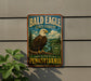 A vintage metal sign for Bald Eagle State Forest in Pennsylvania, featuring an eagle perched on a tree branch against a scenic background.