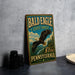 A vintage-style metal sign for the Bald Eagle State Forest in Pennsylvania, featuring an illustration of a bald eagle in flight against a scenic landscape.