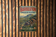 A vintage metal sign with the text "BARBETON MAKHONJWA MOUNTAINS" and "Explore Earth's oldest mountains SOUTH AFRICA" is displayed on a wooden wall.