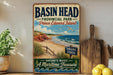 A vintage-style metal sign for "Basin Head Provincial Park" in Prince Edward Island, featuring a beach scene with a bird flying over the water.