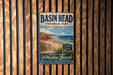 A vintage-style metal sign for Basin Head Provincial Park, Prince Edward Island, featuring a beach scene with a bird flying overhead.