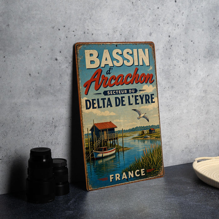 A vintage metal sign advertising Bassin d'Arçon, a fishing village in France, with a seascape and a small boat on the water.