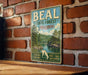 A vintage metal sign for the Beal State Forest in Missouri, featuring a scenic landscape with a river and trees.