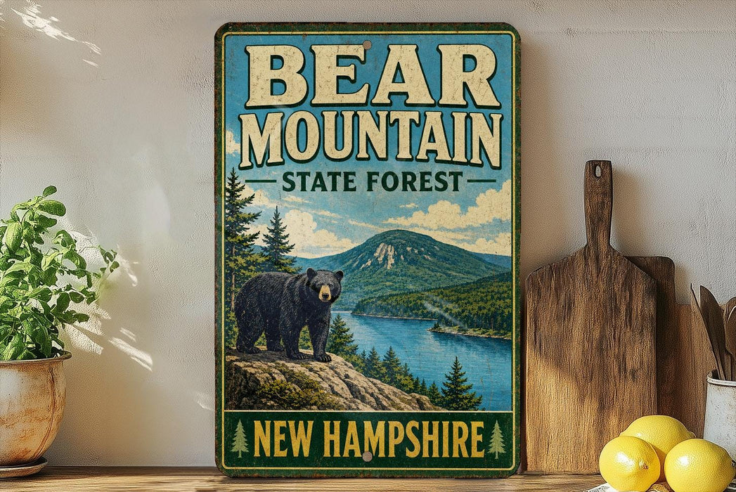 A vintage-style metal sign for Bear Mountain State Forest in New Hampshire, featuring a black bear standing on a rocky outcropping overlooking a lake surrounded by pine trees.