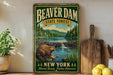 A vintage-style metal sign for Beaver Dam State Forest in New York, featuring a beaver in a natural setting with a waterfall and forest.