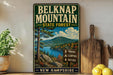 A vintage-style metal sign for Belknap Mountain, New Hampshire, featuring a scenic landscape with a mountain, lake, and forest.
