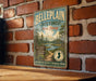 A vintage metal sign for Bellplain State Forest in New Jersey, featuring a scenic illustration of pine trees and a river.