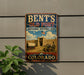 A vintage-style metal sign for Bent's Old Fort, a National Historic Site in Colorado, featuring a wagon and a castle in the background.