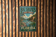 A vintage-style metal sign for Big Shoals State Forest in Florida, featuring a scenic illustration of a river and forest landscape.
