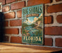 A vintage-style metal sign for Big Shoals State Forest in Florida, featuring a scenic illustration of a river and forest landscape.