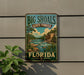 A vintage-style metal sign for Big Shoals State Forest in Florida, featuring a scenic landscape with a river, pine trees, and a cloudy sky.