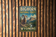 A vintage-style metal sign for the Big Horn National Forest in Wyoming, featuring a large image of a bighorn sheep against a mountainous landscape.