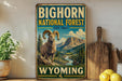 A vintage-style sign for the Big Horn National Forest in Wyoming, featuring a large image of a bighorn sheep in a mountainous landscape.