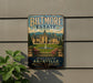 A vintage-style metal sign for Biltmore Estate, featuring an illustration of the estate's historic architecture and landscaping.