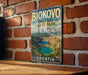 A vintage metal sign displaying the name "BIOKOVO IMOTSKI LAKES PARK" and the word "CROATIA" is hanging on a brick wall.