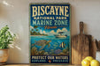 A vintage-style metal sign for Biscayne National Park's Marine Zone, featuring illustrations of marine life and a lighthouse, along with the text "PROTECT OUR WATERS EXPLORE PRESERVE".