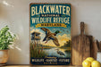 A vintage-style metal sign for the Blackwater National Wildlife Refuge in Maryland, featuring an illustration of ducks and a bird in flight over a body of water.