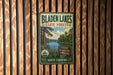 A vintage metal sign for Bladen Lakes State Forest in North Carolina, featuring a scenic image of the lake surrounded by pine trees.