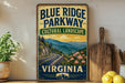 A vintage-style sign for Blue Ridge Parkway, featuring a scenic mountain landscape with a winding road and flowers, is displayed on a shelf next to a wooden cutting board and some lemons.