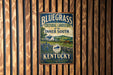 A vintage-style metal sign with the text "BLUEGRASS CULTURAL LANDSCAPE OF THE INNER SOUTH KENTUCKY" displayed on a wooden wall.