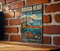 A vintage-style metal sign for the Bodegra Head State Marine Reserve in California, featuring an illustration of a rocky coastline, ocean, and marine life.