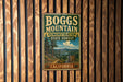 A vintage metal sign for Boggs Mountain, a demonstration state forest in California, is displayed on a wooden wall.