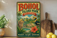 A vintage-style poster advertising BOHOL ISLAND PARK, featuring a tropical landscape with a bird, palm trees, and a waterfall.