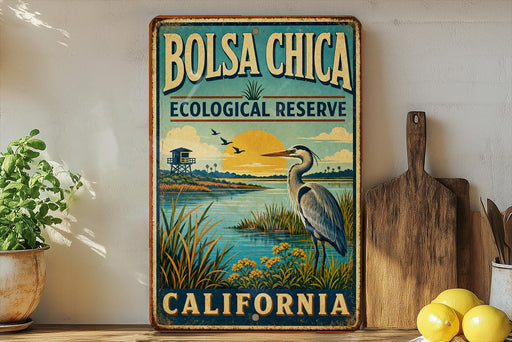A vintage-style metal sign for the Bolsa Chica Ecological Reserve in California, featuring a bird and a sunset landscape.