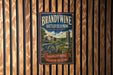 A vintage-style metal sign for Brandywine Battlefield Park in Pennsylvania, featuring an illustration of a cannon and a monument, mounted on a wooden wall.