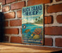 A vintage-style metal sign for the Buck Island Reef National Monument, featuring an illustration of a tropical beach scene with a turtle, coral, and fish.