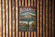 A vintage-style metal sign with the text "THE PEARL OF THE DANUBE BUDAPEST" and "BUNDA CASTLE QUARTER" is displayed on a wooden wall.