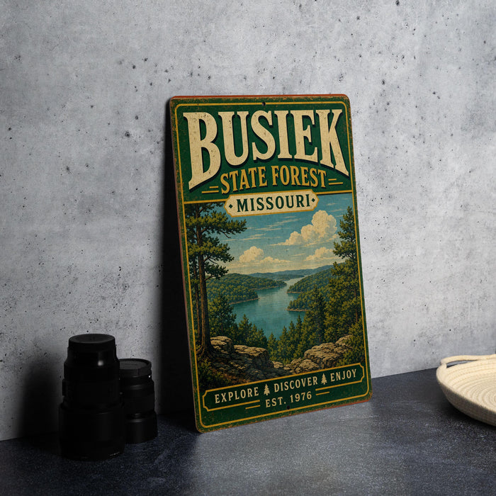 A vintage-style metal sign for Busiak State Forest, Missouri, featuring a scenic landscape with a lake and mountains.