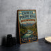 A vintage metal sign for the Cache la Poudre River National Heritage Area in Colorado, featuring a scenic illustration of the river surrounded by mountains and forests.