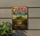 A vintage metal sign advertising the Cahokia Mounds State Historic Site in Illinois, featuring a mountain landscape and the text "Cahokia Mounds State Historic Site" and "ILLINOIS EXPLORE LEARN DISCOVER Preserving Our Ancient Heritage".