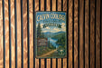 A vintage metal sign for Calvin Coolidge State Forest in Vermont, featuring a scenic image of a forest and a lake.