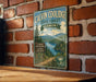 A vintage metal sign for Calvin Coolidge State Forest in Vermont, featuring a scenic landscape with a lake and mountains.
