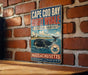 A vintage-style metal sign with the text "Cape Cod Bay Right Whale Critical Habitat" and "Massachusetts" printed on it, mounted on a brick wall.