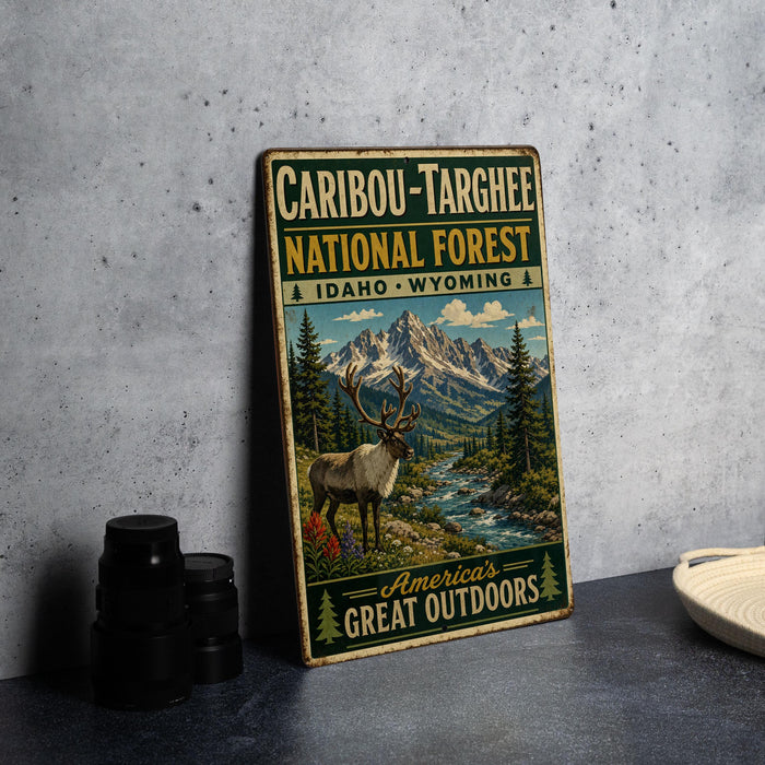 A vintage-style metal sign advertising the Caribbean-Targhee National Forest in Idaho, Wyoming, featuring a deer and mountain landscape.