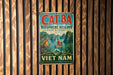 A vintage metal sign with the text "Cat Ba Bioscape Reserve Nature in Harmony" and "Viet Nam Heritage for the Future" is displayed on a wooden wall.