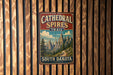 A vintage metal sign for the Cathedral Spires Trail in South Dakota is displayed on a wooden wall.