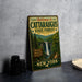 A vintage-style metal sign welcoming visitors to the Cataraugus State Forest in New York, featuring a scenic image of a waterfall surrounded by lush greenery.