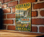 A vintage metal sign with text and illustrations, mounted on a brick wall.