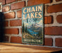 A vintage-style metal sign for Chain Lakes Loop in Washington, featuring a mountain landscape and a lake.