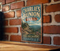 A vintage-style metal sign for Charlie's Bunch Trail in Tennessee, featuring a scenic mountain landscape with pine trees and flowers.