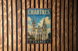 A vintage metal sign with the text "CHARTRES CATHEDRAL FRANCE" and an illustration of the Chartres Cathedral in France.
